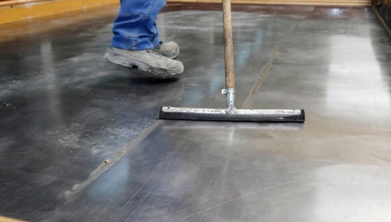 Die behandelte Schalung wird mit einem Gummischieber abgezogen.