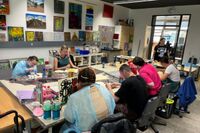 Personen malen an einem großen Tisch.