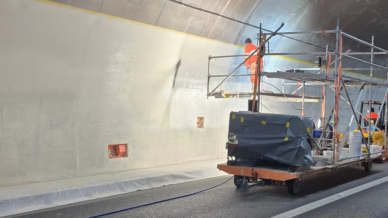 Verarbeiter beschichtet die Tunnelwand auf einem Gerüst