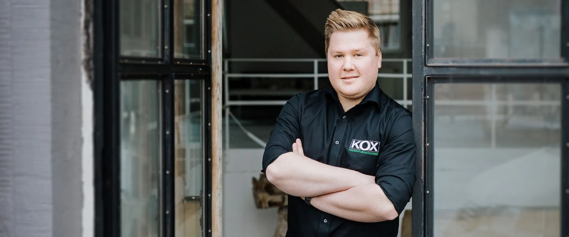 Dennis Kox vor einem Gebäude mit verschränkten Armen.