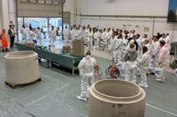 Ein Vortrag wird gehalten, alle Personen tragen weiße Anzüge.