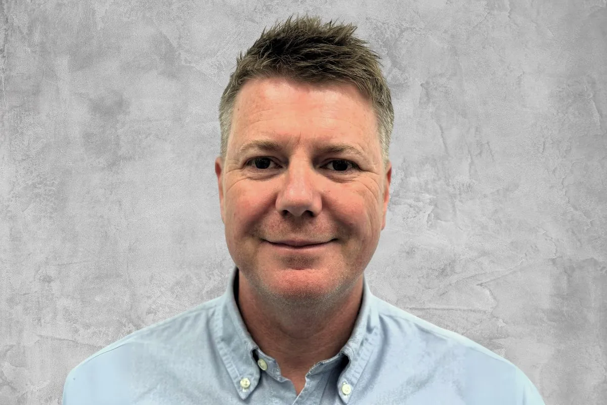 Portrait von Greg Burton vor grauem Hintergrund.