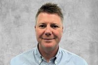 Portrait von Greg Burton vor grauem Hintergrund.