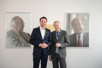Drei Generationen der Unternehmerfamilie Müller: Dr. Claus-M. Müller mit seinem Sohn Nicolaus vor den Porträts seines Vaters und Firmengründers Heinrich W. Müller (links; †2010) und seines Bruders Dr. Bertram R. Müller (†2012).