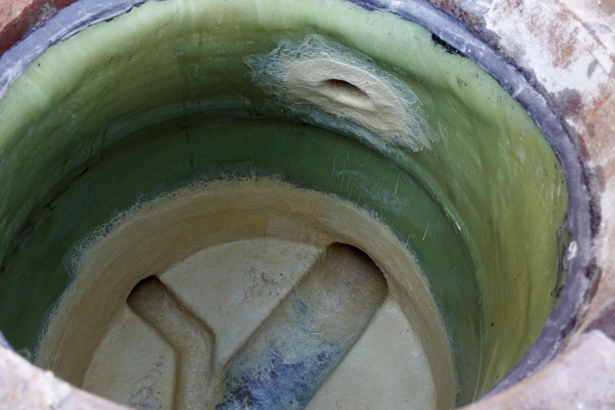 Blick in einen Schacht, der mit dem Vertiliner®-Komplettsystem saniert worden ist: In beige sind die Bermen- und Gerinnebeschichtung sowie Rohranbindungen mit dem Ortlaminat ombran SC zu sehen und in Grün der Vertiliner®. Der obere Abschluss des Vertiliners erfolgt mit Konudur Flexfit, dem zweikomponentigen, dauerhaft flexiblen Spezialreaktionsharz der MC-Bauchemie mit DIBt-Zulassung für die Lineranbindung in Schachtbauwerken.